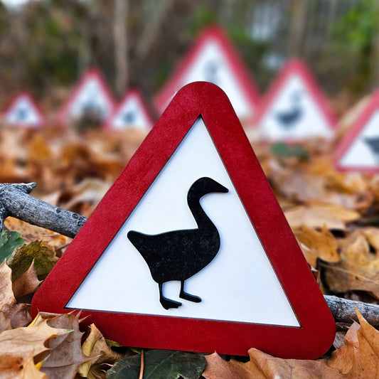Warning sign with a goose symbol on a background of autumn leaves and more warning signs.